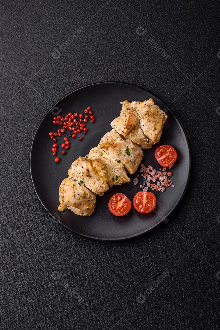 Delicioso kebab de carne de frango fresco com sal, especiarias e ervas sobre um fundo escuro de concreto