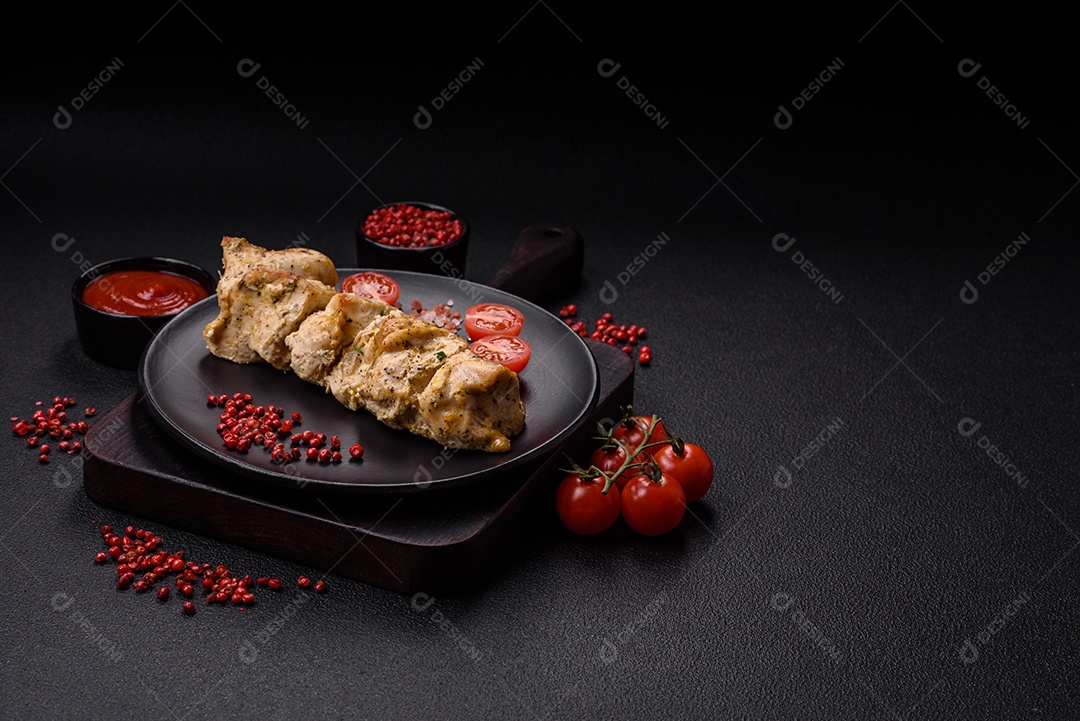 Delicioso kebab de carne de frango fresco com sal, especiarias e ervas sobre um fundo escuro de concreto