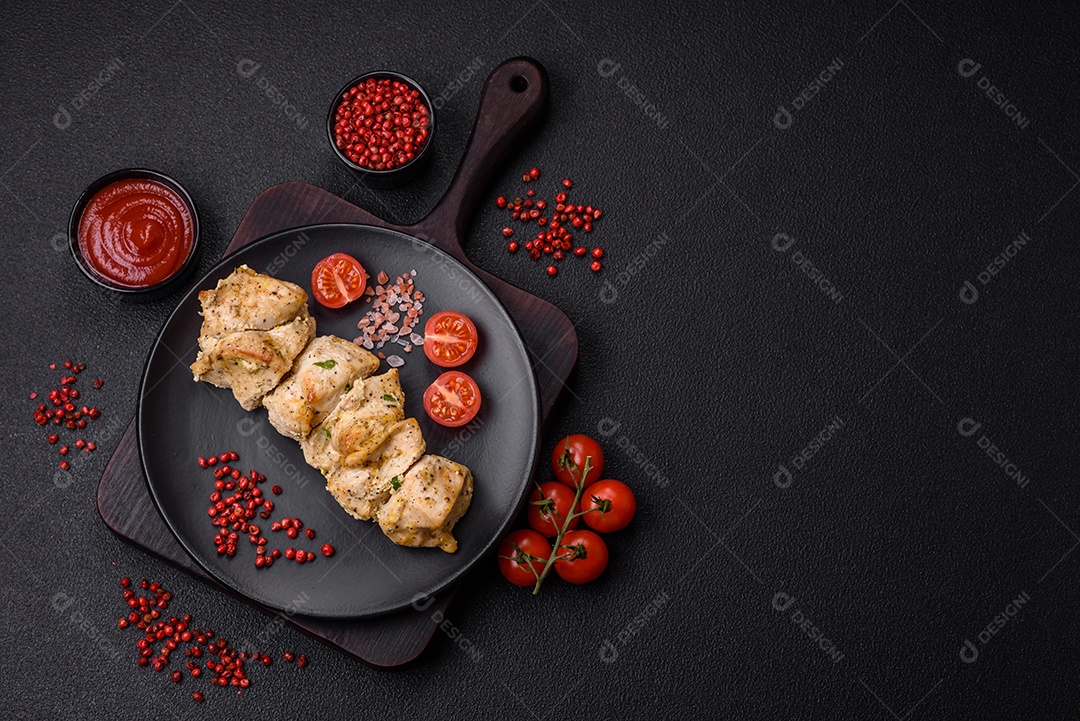 Delicioso kebab de carne de frango fresco com sal, especiarias e ervas sobre um fundo escuro de concreto