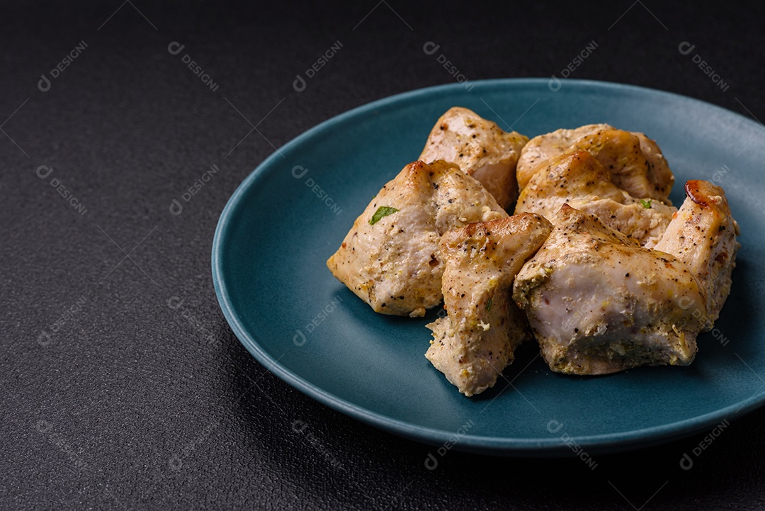 Delicioso kebab de carne de frango fresco com sal, especiarias e ervas sobre um fundo escuro de concreto