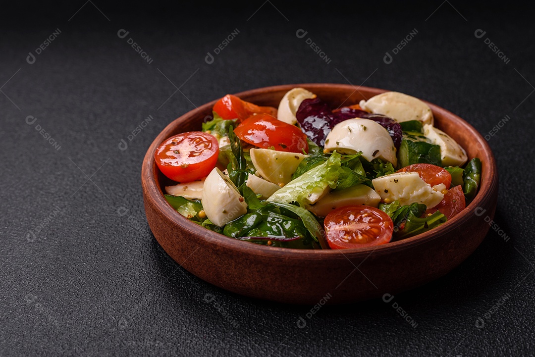 Deliciosa salada caprese fresca com mussarela, tomate, verduras com sal, especiarias e ervas sobre fundo escuro de concreto