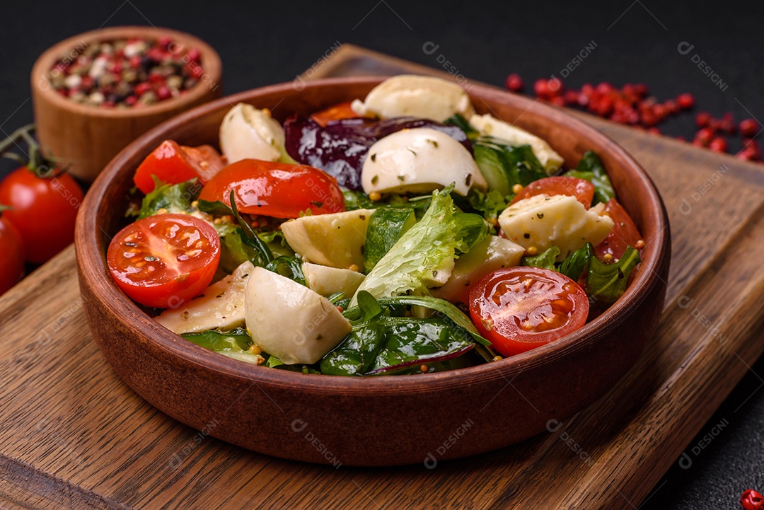 Deliciosa salada caprese fresca com mussarela, tomate, verduras com sal, especiarias e ervas sobre fundo escuro de concreto