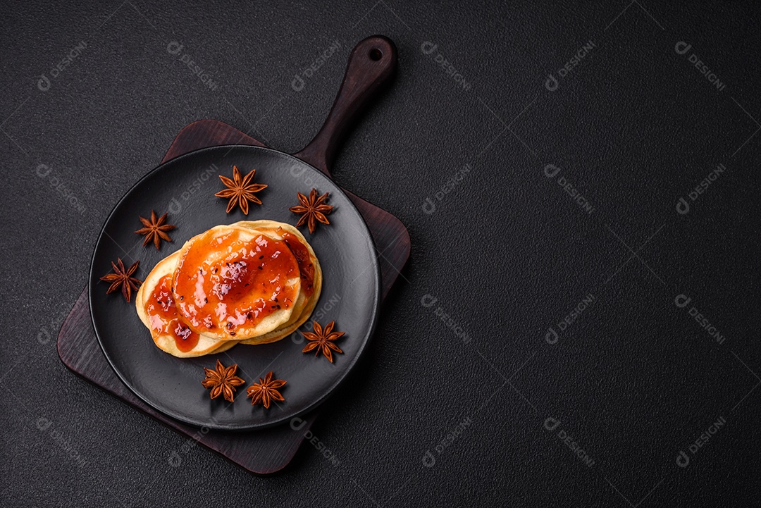 Panquecas recém-assadas com geléia deliciosa em uma placa de cerâmica sobre um fundo escuro de concreto