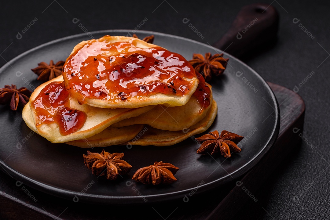 Panquecas recém-assadas com geléia deliciosa em uma placa de cerâmica sobre um fundo escuro de concreto