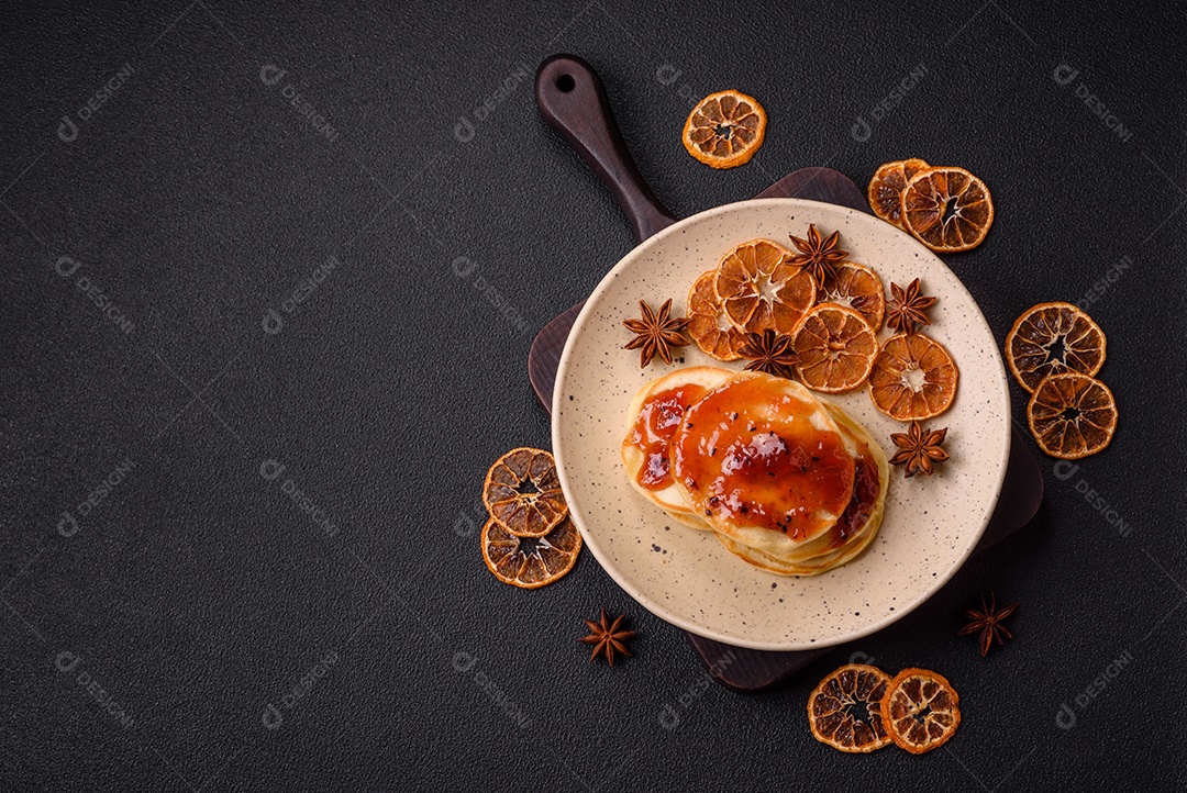 Panquecas recém-assadas com geléia deliciosa em uma placa de cerâmica sobre um fundo escuro de concreto