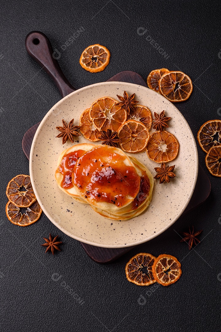 Panquecas recém-assadas com geléia deliciosa em uma placa de cerâmica sobre um fundo escuro de concreto