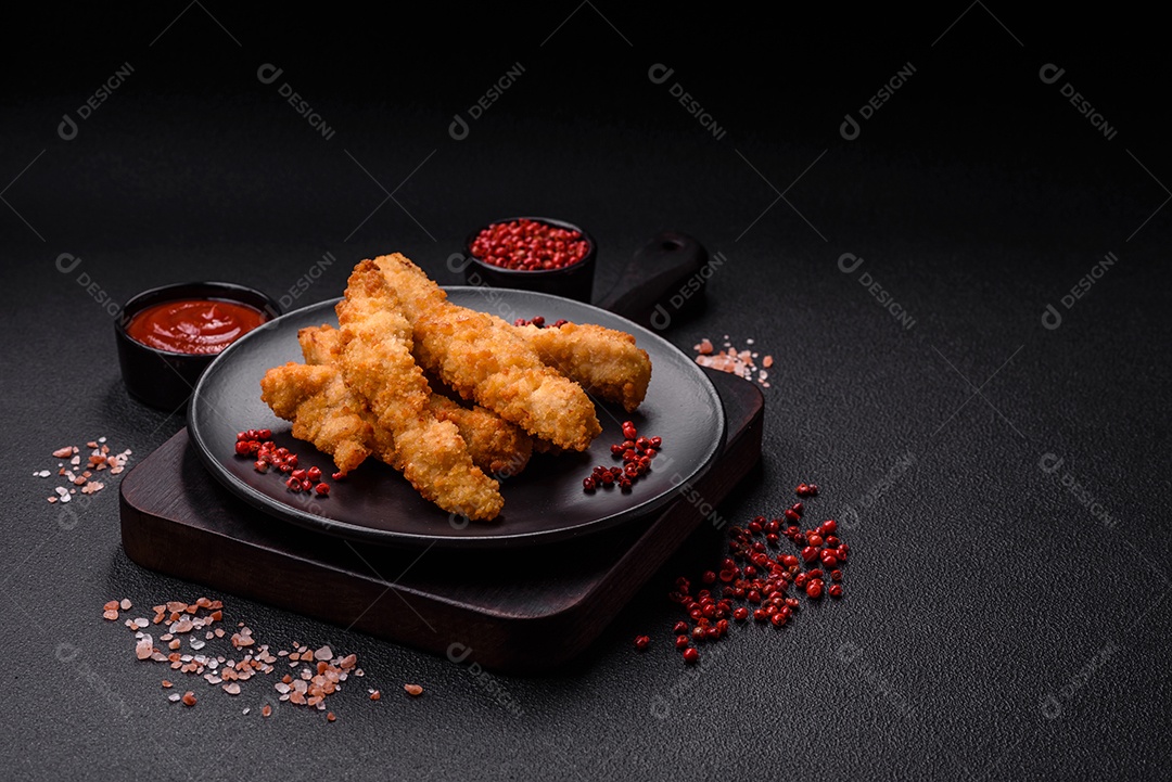 Deliciosas tiras de frango ou peru fresco ou nuggets empanados com sal e especiarias sobre um fundo escuro de concreto