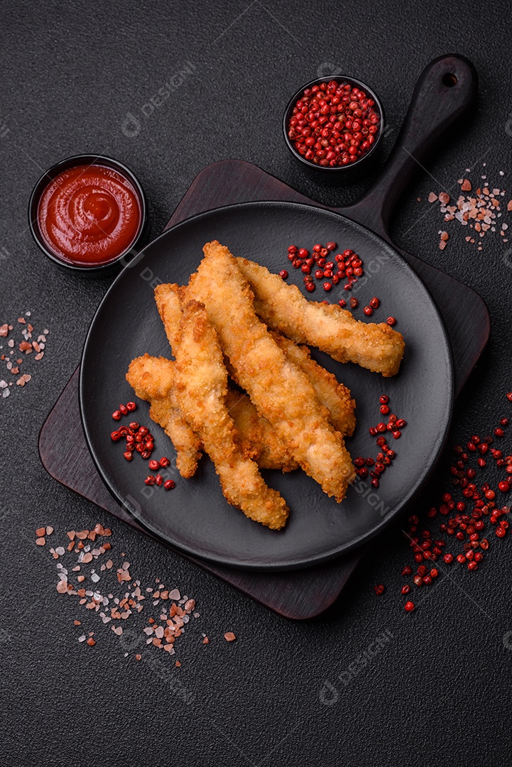 Deliciosas tiras de frango ou peru fresco ou nuggets empanados com sal e especiarias sobre um fundo escuro de concreto