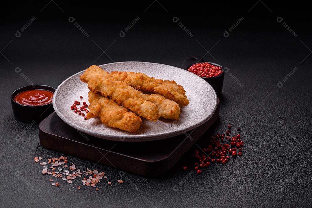 Deliciosas tiras de frango ou peru fresco ou nuggets empanados com sal e especiarias sobre um fundo escuro de concreto