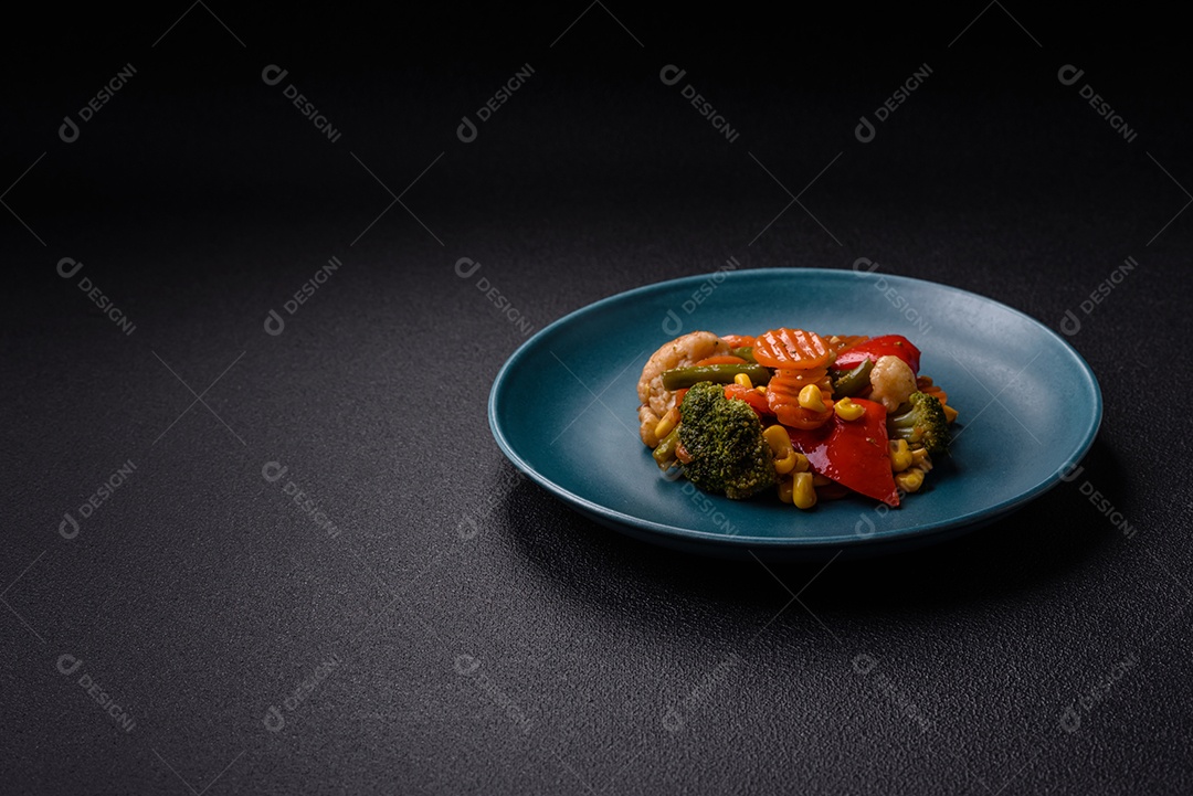 Deliciosos legumes saudáveis ​​cozidos cenouras, brócolis, feijão de espargos e pimentões em um fundo escuro de concreto