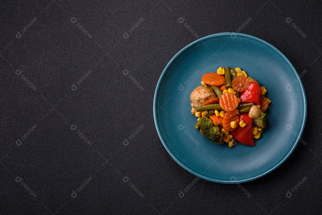 Deliciosos legumes saudáveis ​​cozidos cenouras, brócolis, feijão de espargos e pimentões em um fundo escuro de concreto