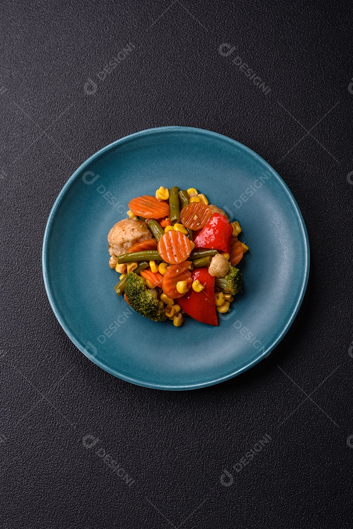 Deliciosos legumes saudáveis ​​cozidos cenouras, brócolis, feijão de espargos e pimentões em um fundo escuro de concreto