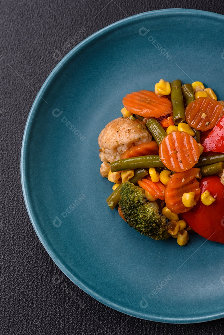 Deliciosos legumes saudáveis ​​cozidos cenouras, brócolis, feijão de espargos e pimentões em um fundo escuro de concreto