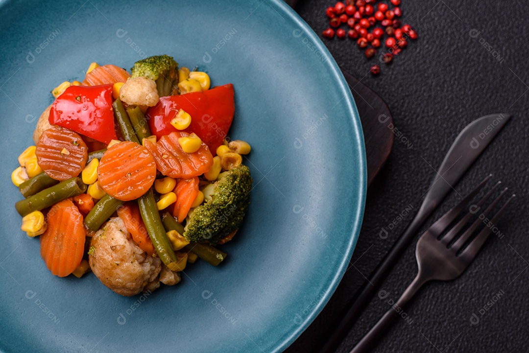 Deliciosos legumes saudáveis ​​cozidos cenouras, brócolis, feijão de espargos e pimentões em um fundo escuro de concreto