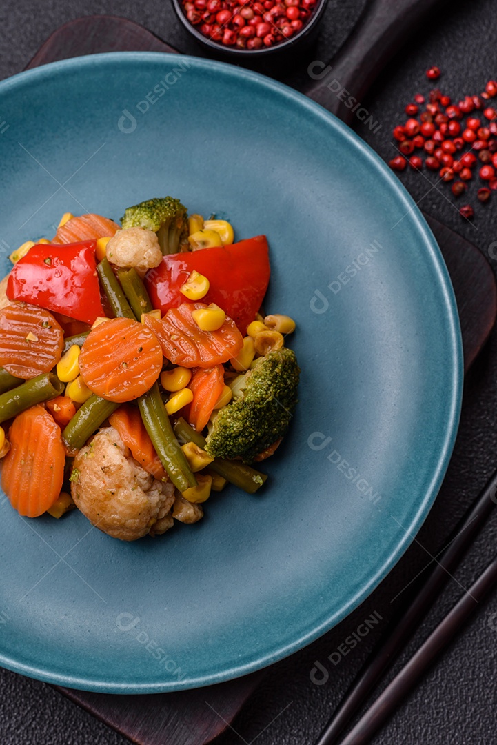 Deliciosos legumes saudáveis ​​cozidos cenouras, brócolis, feijão de espargos e pimentões em um fundo escuro de concreto