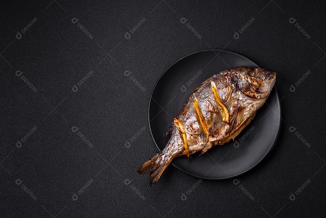 Delicioso dorado assado na grelha com sal, especiarias e ervas sobre um fundo escuro texturizado