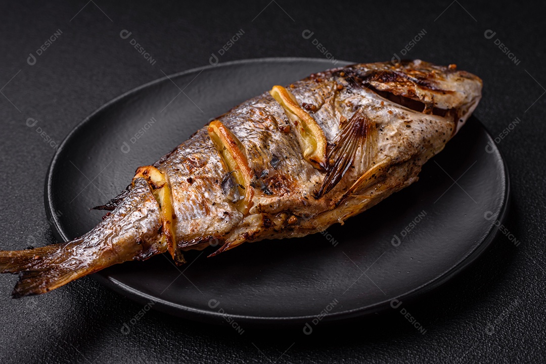Delicioso dorado assado na grelha com sal, especiarias e ervas sobre um fundo escuro texturizado