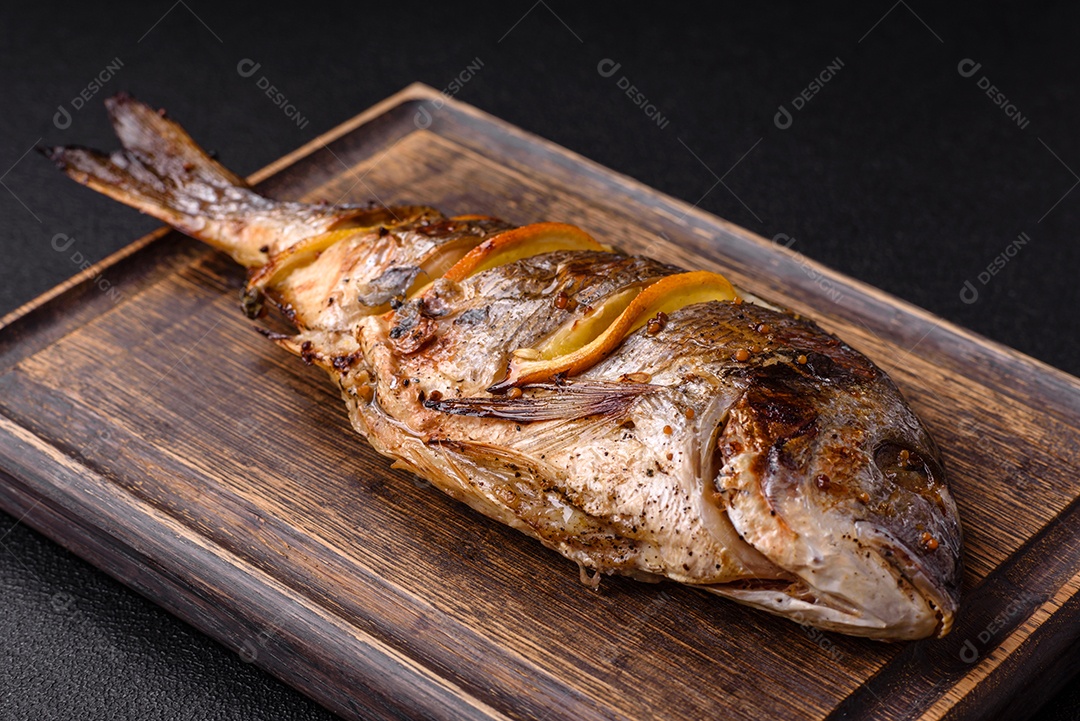 Delicioso dorado assado na grelha com sal, especiarias e ervas sobre um fundo escuro texturizado