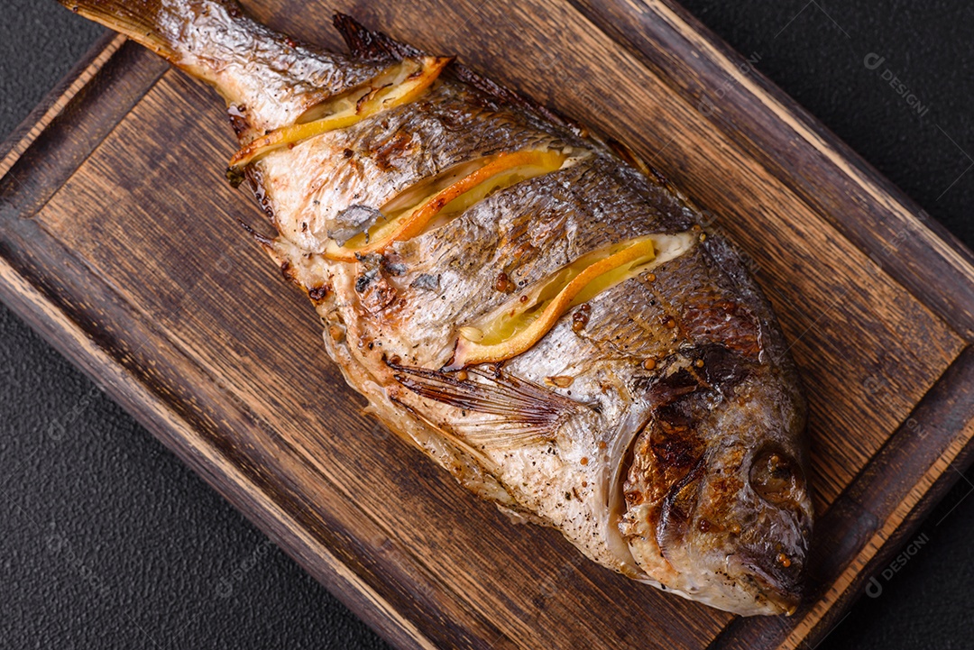 Delicioso dorado assado na grelha com sal, especiarias e ervas sobre um fundo escuro texturizado