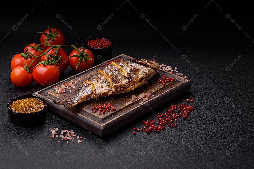 Delicioso dorado assado na grelha com sal, especiarias e ervas sobre um fundo escuro texturizado