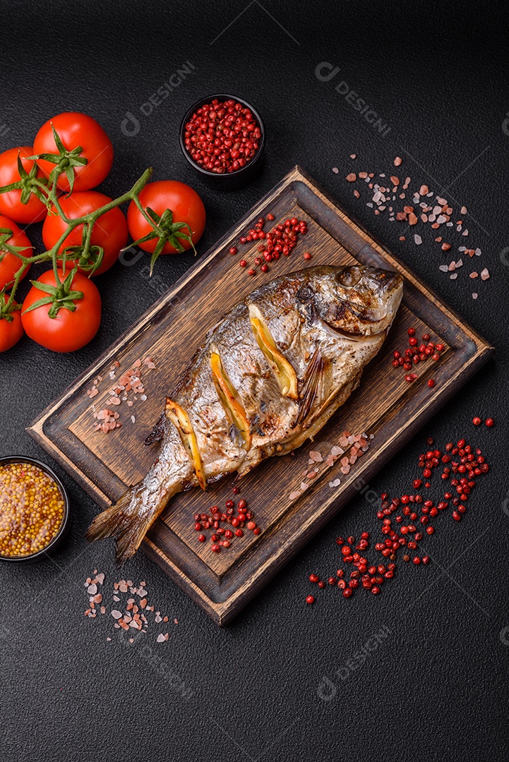 Delicioso dorado assado na grelha com sal, especiarias e ervas sobre um fundo escuro texturizado