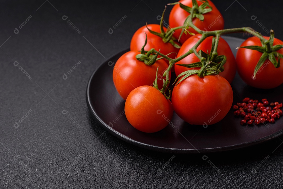 Tomates cereja vermelhos frescos em um galho sobre um fundo escuro de concreto como ingrediente para preparar um prato em casa