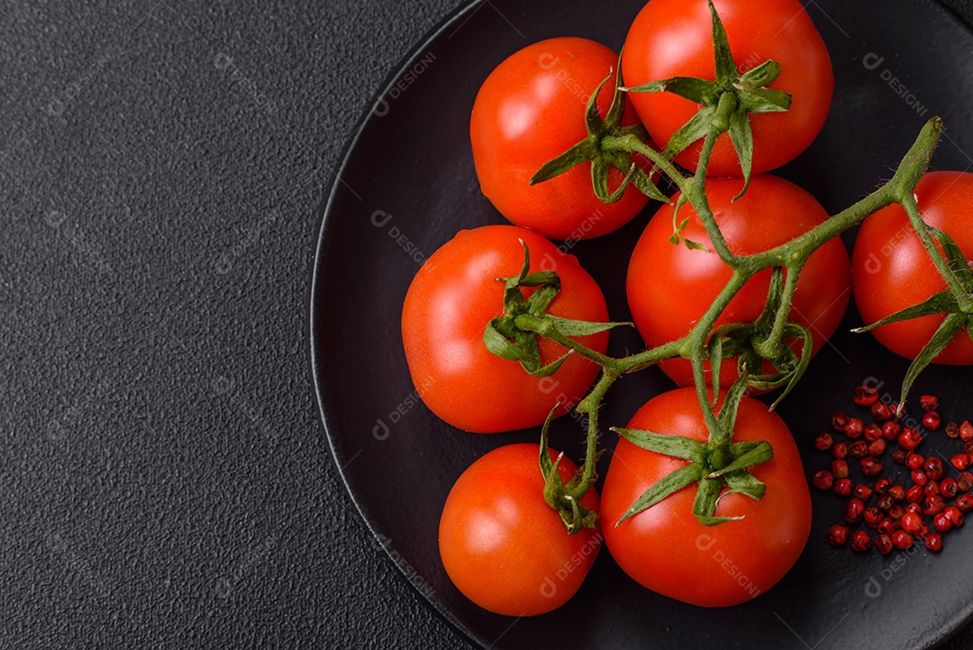 Tomates cereja vermelhos frescos em um galho sobre um fundo escuro de concreto como ingrediente para preparar um prato em casa