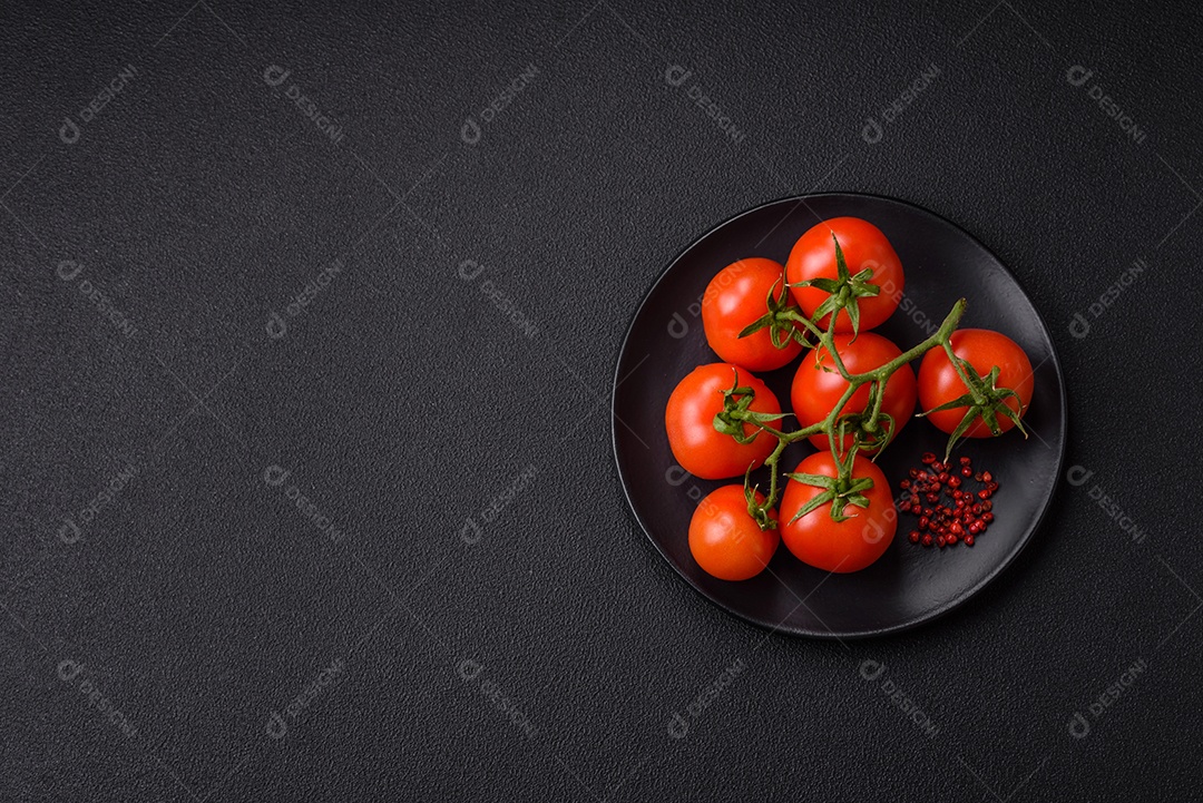 Tomates cereja vermelhos frescos em um galho sobre um fundo escuro de concreto como ingrediente para preparar um prato em casa