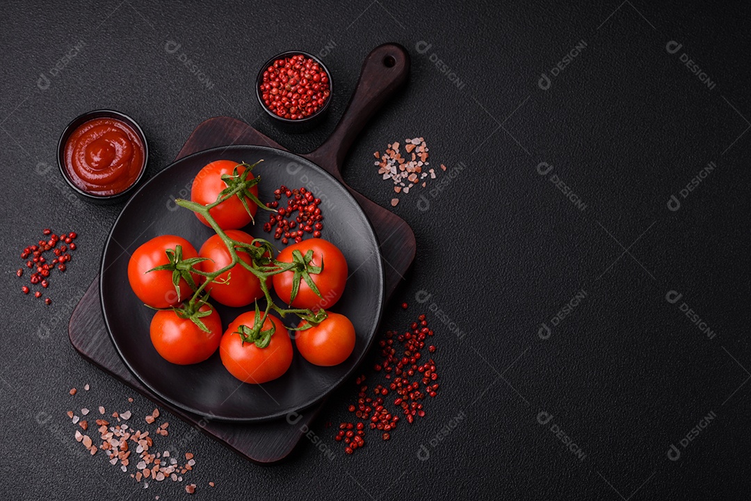 Tomates cereja vermelhos frescos em um galho sobre um fundo escuro de concreto como ingrediente para preparar um prato em casa