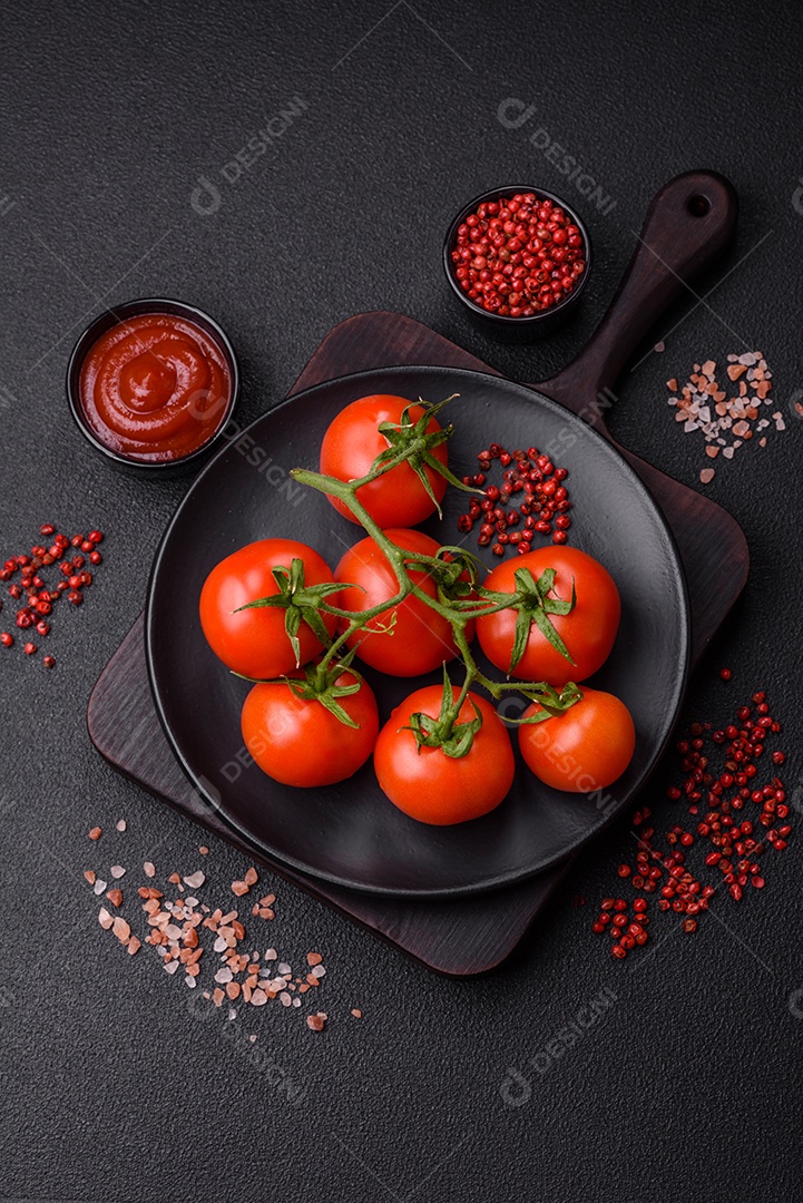 Tomates cereja vermelhos frescos em um galho sobre um fundo escuro de concreto como ingrediente para preparar um prato em casa