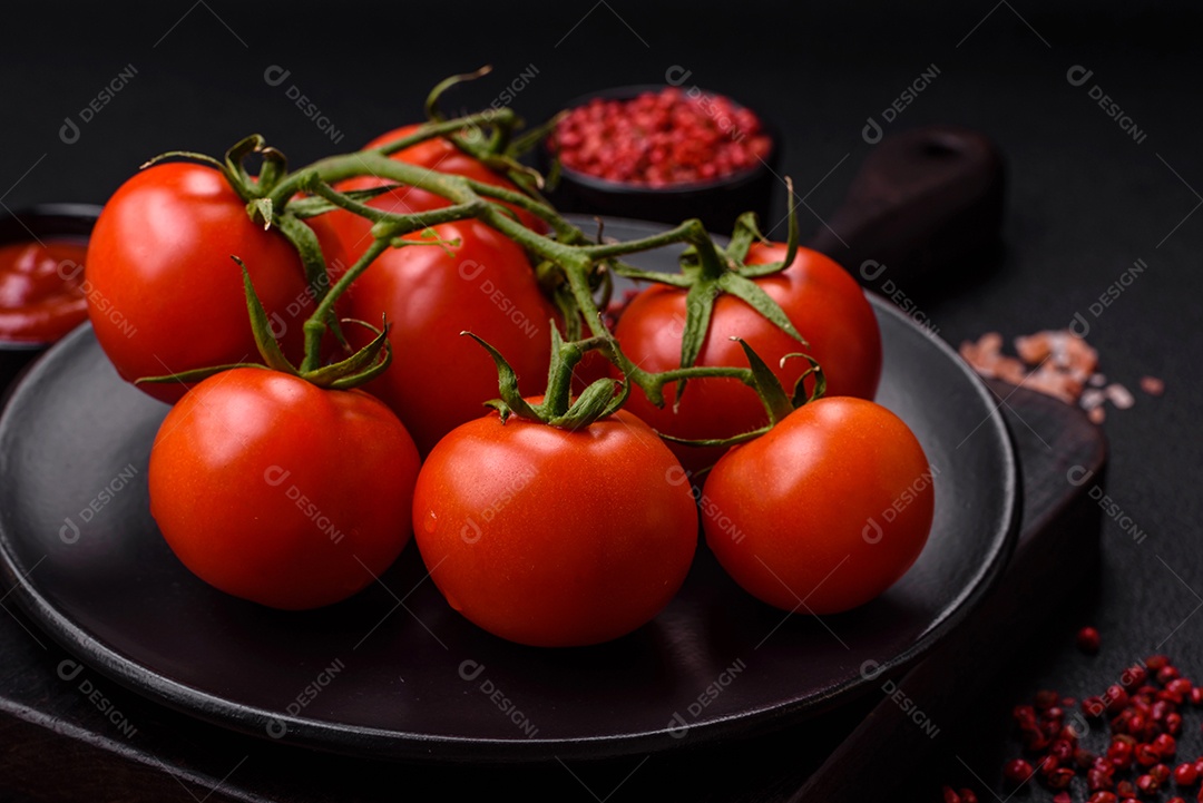 Tomates cereja vermelhos frescos em um galho sobre um fundo escuro de concreto como ingrediente para preparar um prato em casa