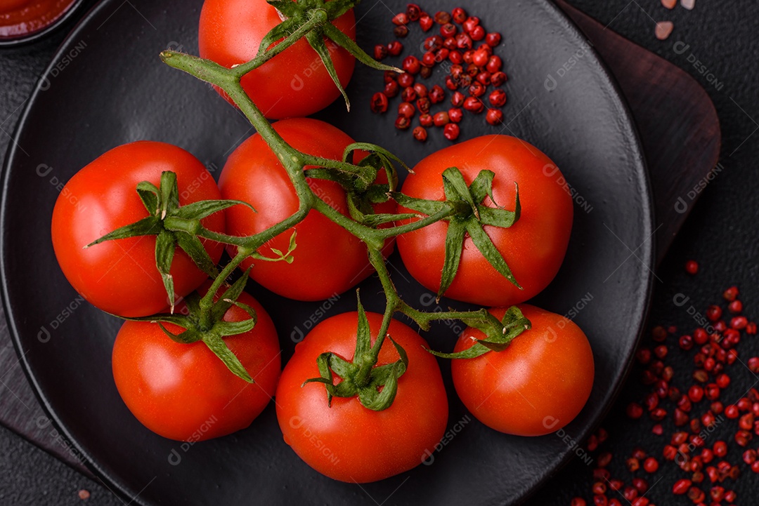 Tomates cereja vermelhos frescos em um galho sobre um fundo escuro de concreto como ingrediente para preparar um prato em casa