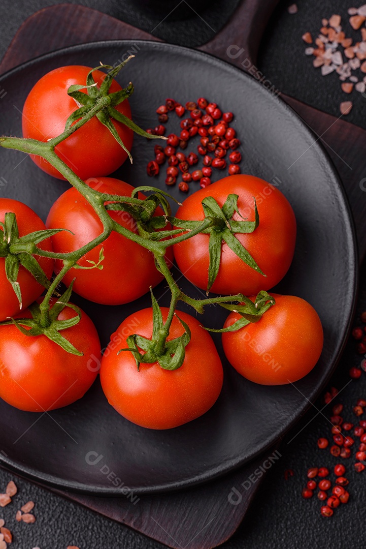 Tomates cereja vermelhos frescos em um galho sobre um fundo escuro de concreto como ingrediente para preparar um prato em casa