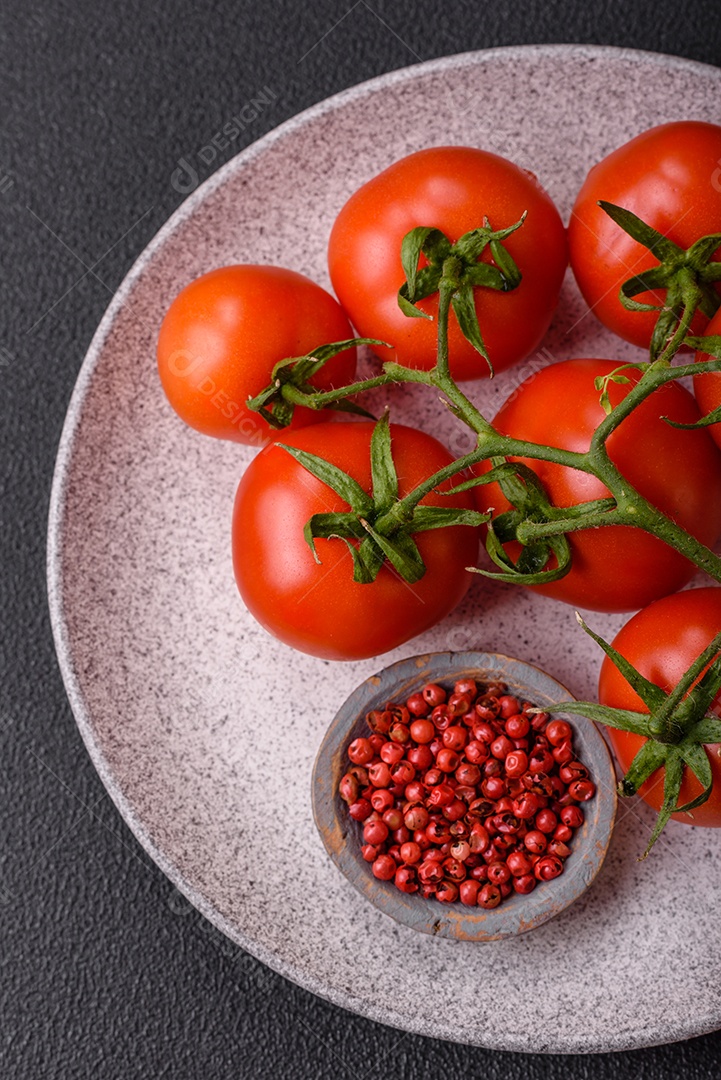 Tomates cereja vermelhos frescos em um galho sobre um fundo escuro de concreto como ingrediente para preparar um prato em casa