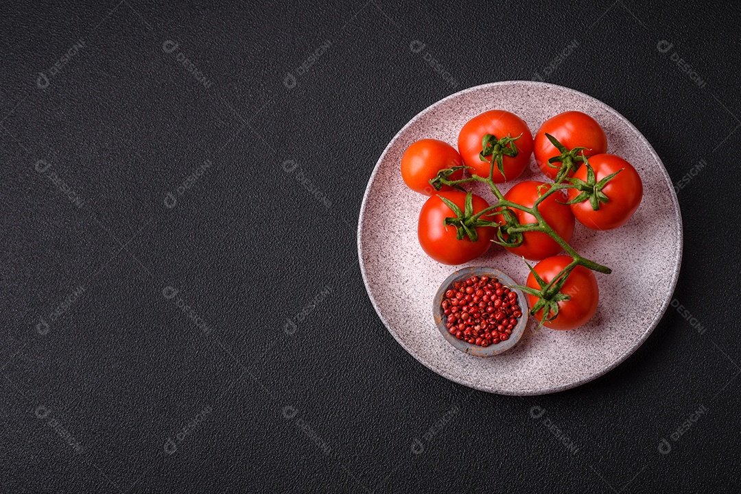 Tomates cereja vermelhos frescos em um galho sobre um fundo escuro de concreto como ingrediente para preparar um prato em casa