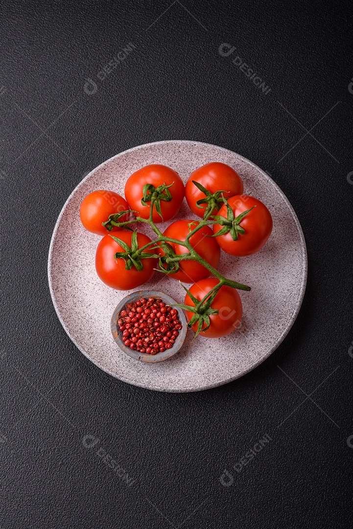 Tomates cereja vermelhos frescos em um galho sobre um fundo escuro de concreto como ingrediente para preparar um prato em casa