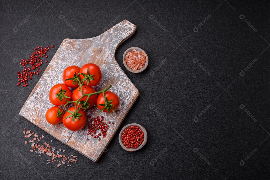 Tomates cereja vermelhos frescos em um galho sobre um fundo escuro de concreto como ingrediente para preparar um prato em casa