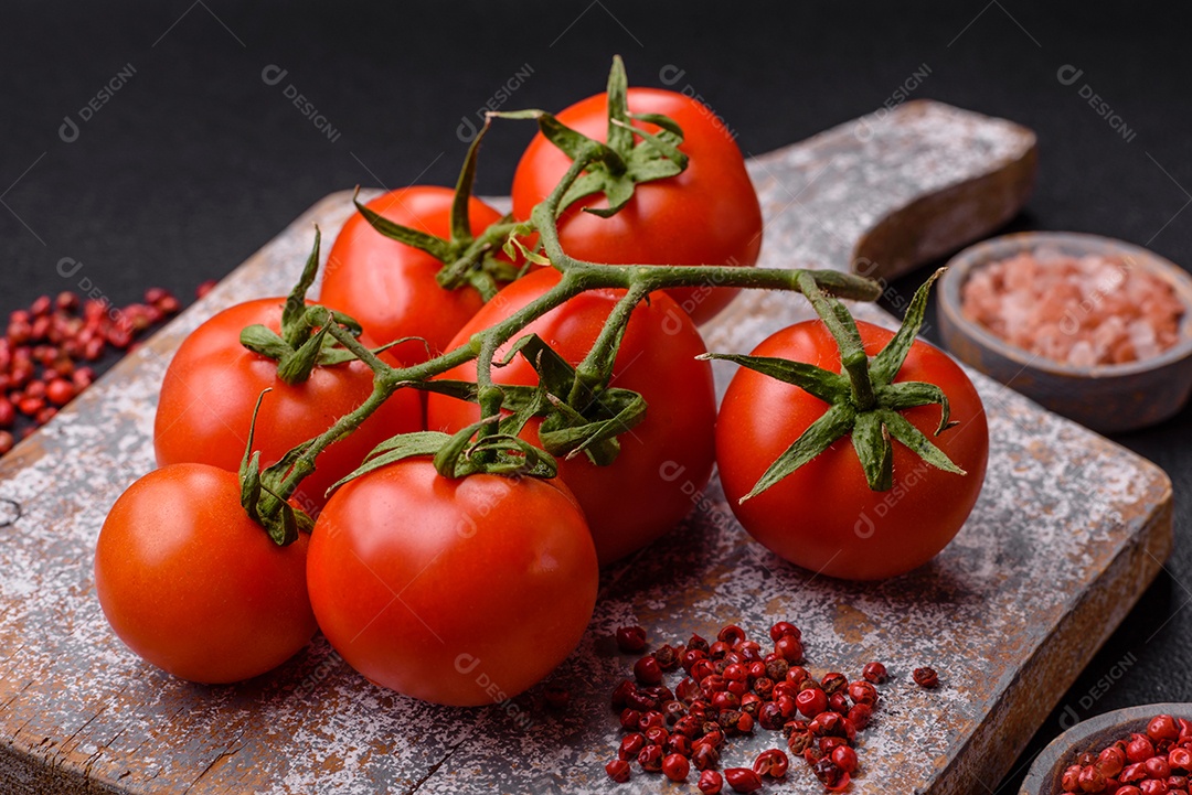 Tomates cereja vermelhos frescos em um galho sobre um fundo escuro de concreto como ingrediente para preparar um prato em casa