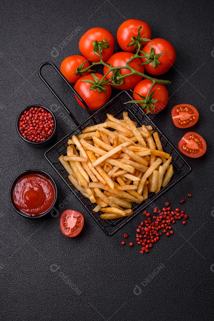 Deliciosas batatas fritas douradas crocantes com sal e especiarias sobre um fundo escuro de concreto