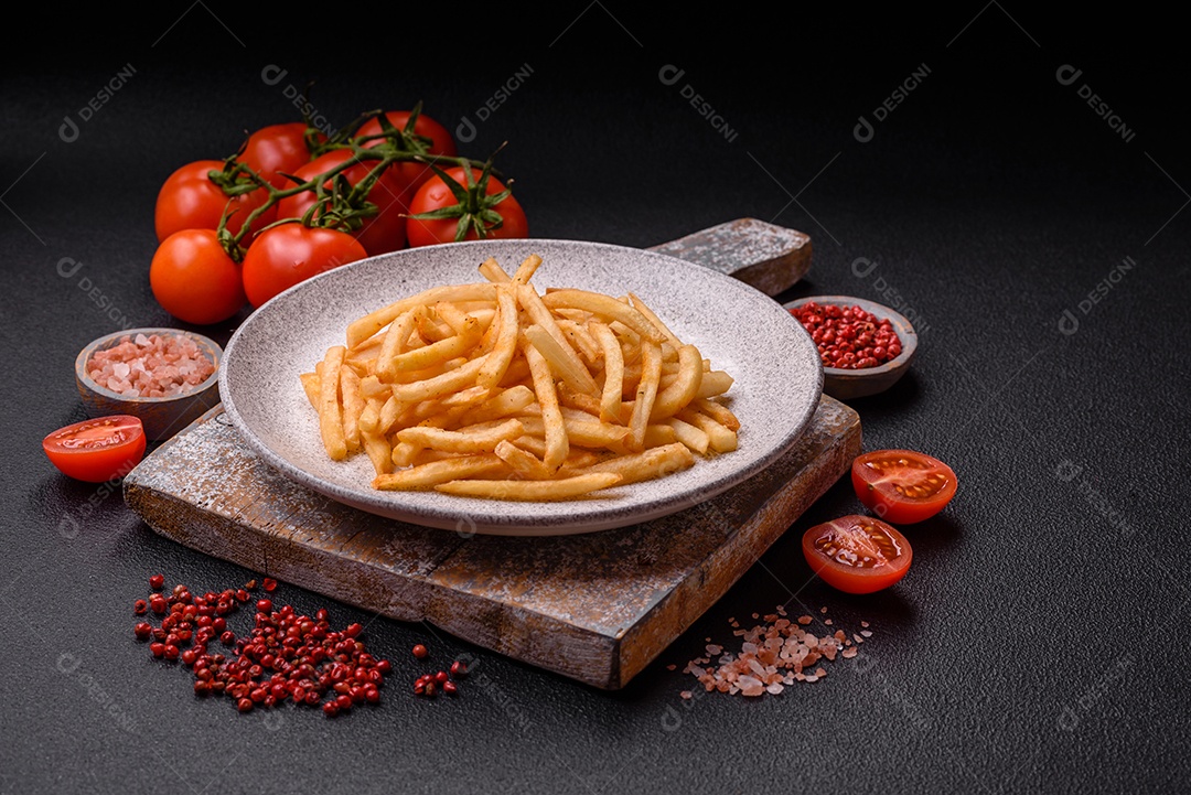 Deliciosas batatas fritas douradas crocantes com sal e especiarias sobre um fundo escuro de concreto