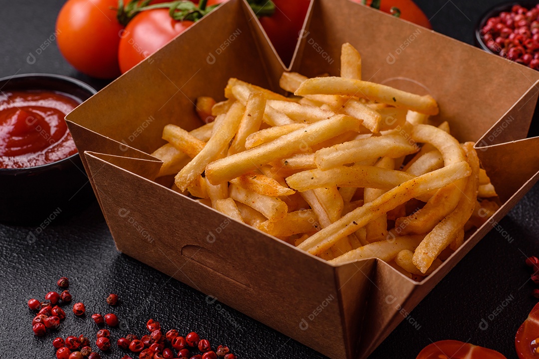 Deliciosas batatas fritas douradas crocantes com sal e especiarias sobre um fundo escuro de concreto