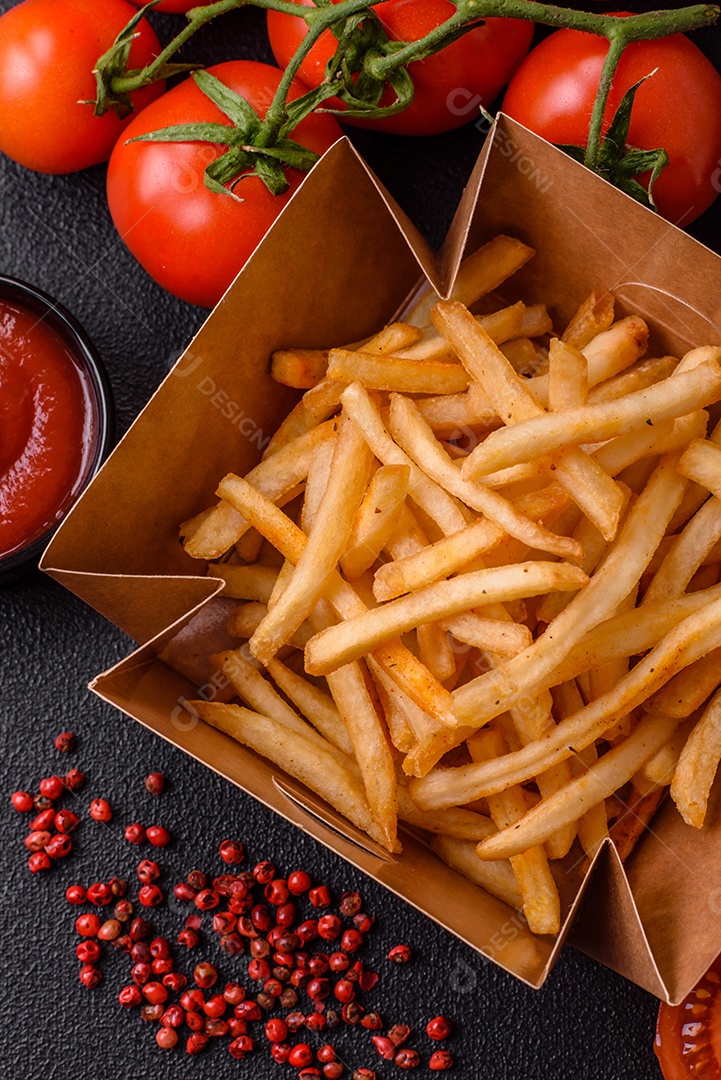 Deliciosas batatas fritas douradas crocantes com sal e especiarias sobre um fundo escuro de concret