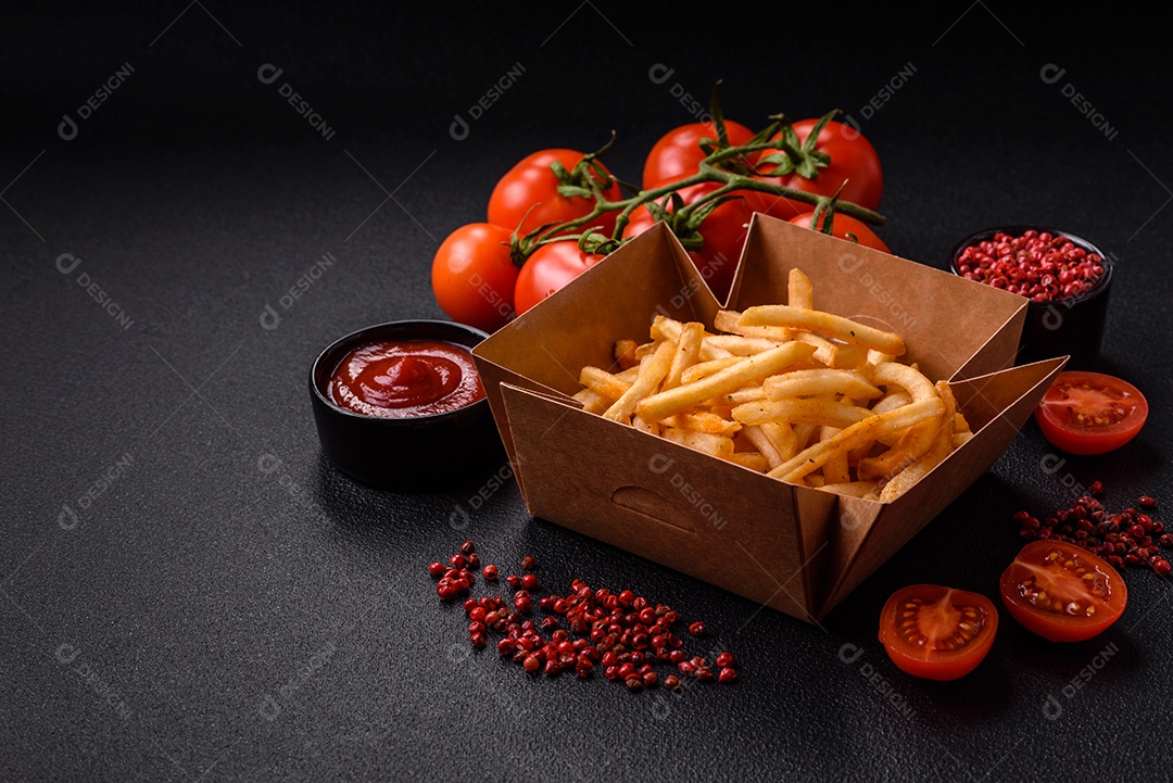 Deliciosas batatas fritas douradas crocantes com sal e especiarias sobre um fundo escuro de concreto