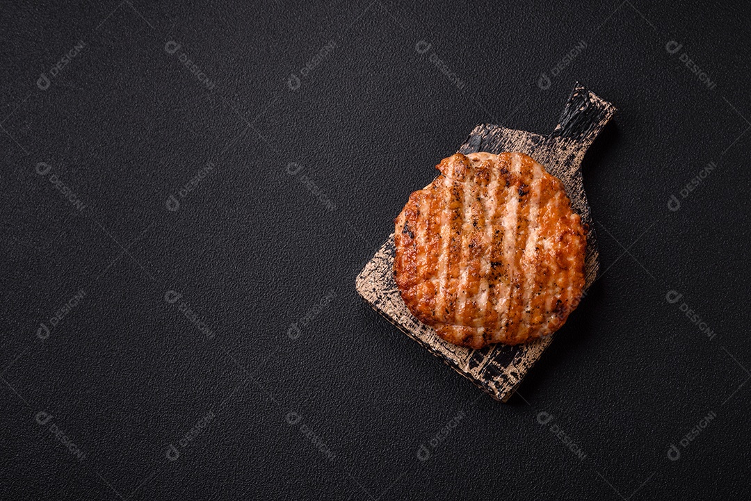 Delicioso filé de frango grelhado fresco com especiarias e ervas em um fundo escuro de concreto. Um prato cozido no fogo