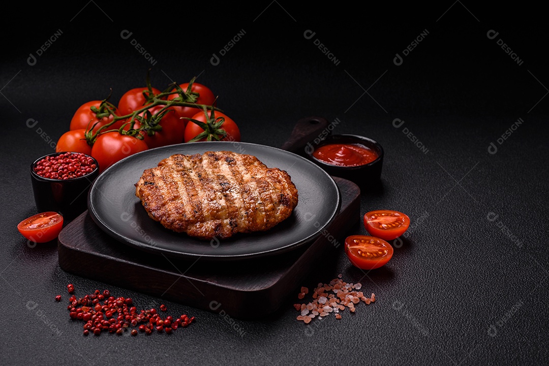 Delicioso filé de frango grelhado fresco com especiarias e ervas em um fundo escuro de concreto. Um prato cozido no fogo