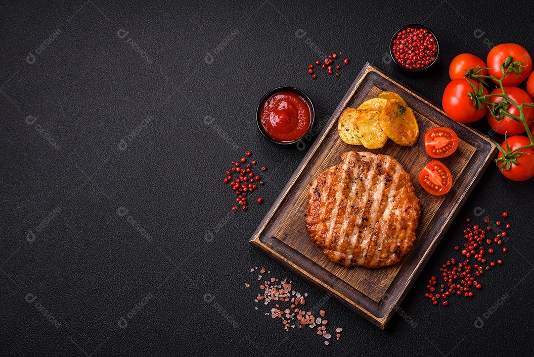 Delicioso filé de frango grelhado fresco com especiarias e ervas em um fundo escuro de concreto. Um prato cozido no fogo