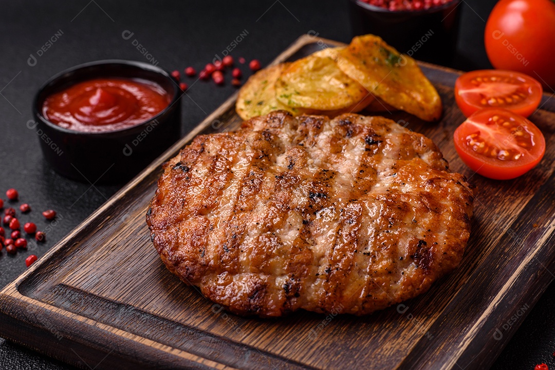 Delicioso filé de frango grelhado fresco com especiarias e ervas em um fundo escuro de concreto. Um prato cozido no fogo