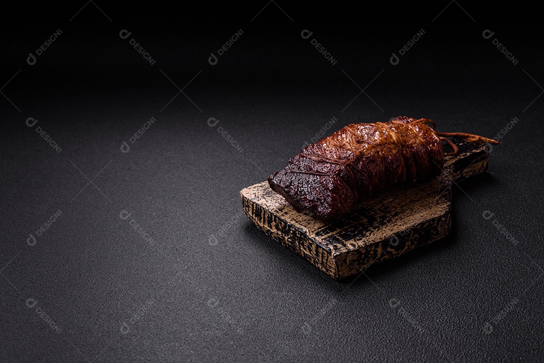 Delicioso peito de frango de carne defumada com sal, especiarias e ervas sobre um fundo escuro de concreto