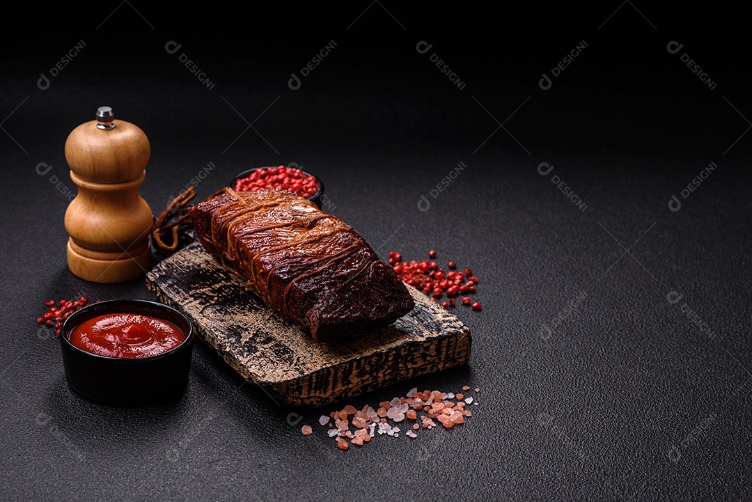 Delicioso peito de frango de carne defumada com sal, especiarias e ervas sobre um fundo escuro de concreto