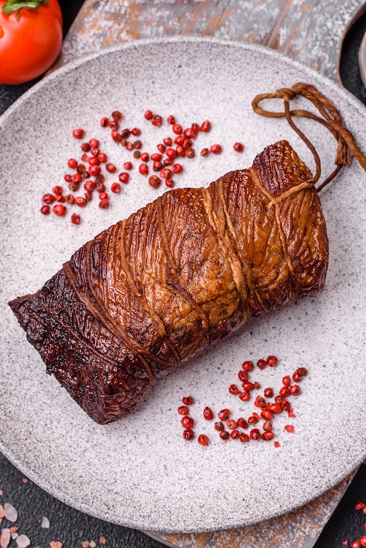Delicioso peito de frango de carne defumada com sal, especiarias e ervas sobre um fundo escuro de concreto